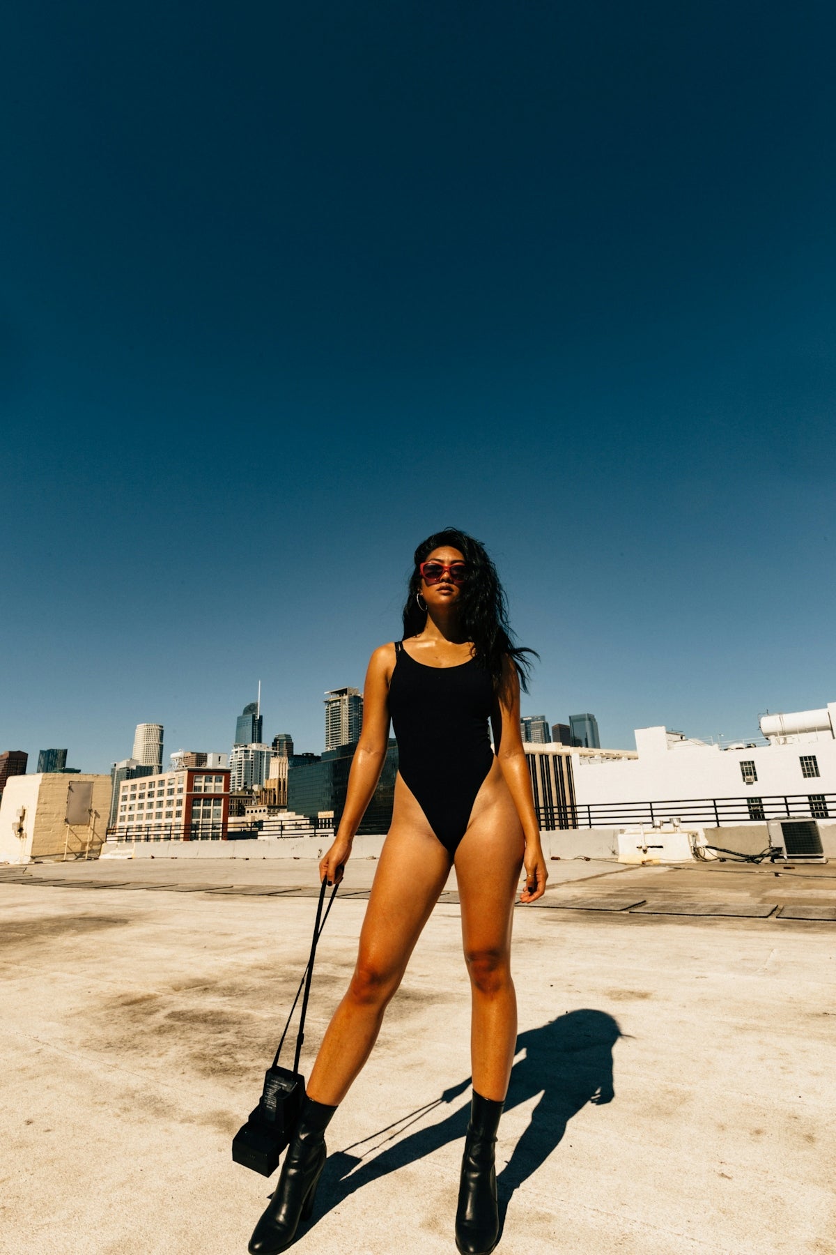 woman in black bodysuit holding black crossbody bag