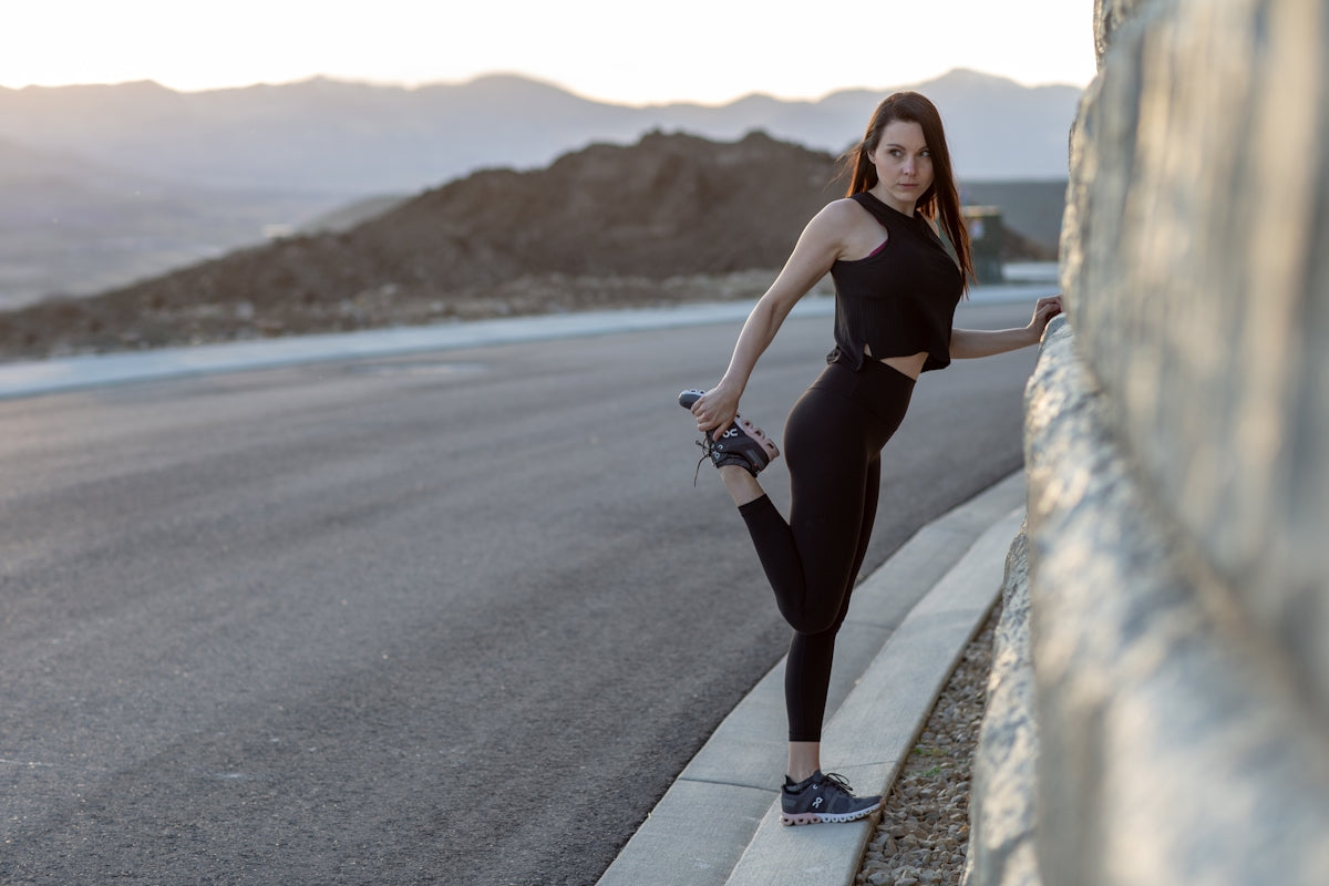 woman in black tank top and black leggings walking on gray concrete road during daytime