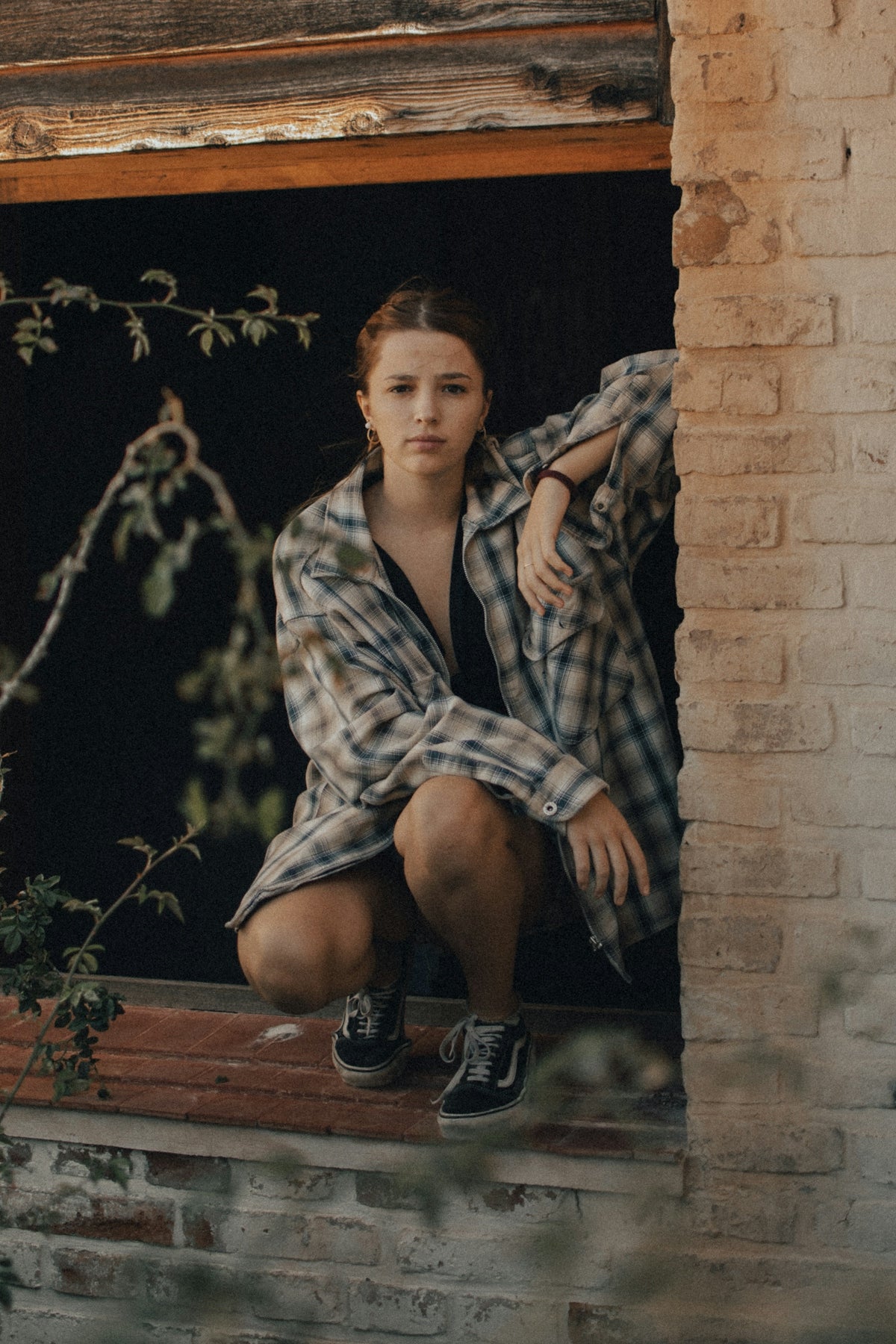 woman in black and white plaid dress shirt sitting on brown wooden seat