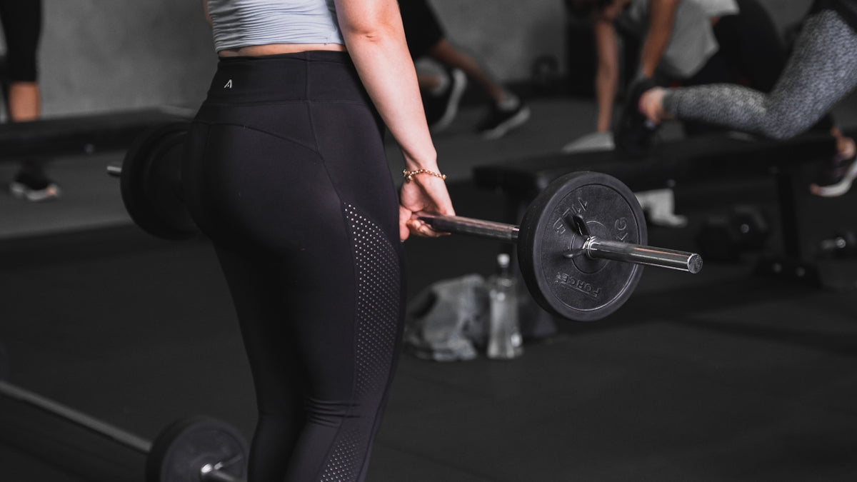 a woman lifting a barbell in a gym
