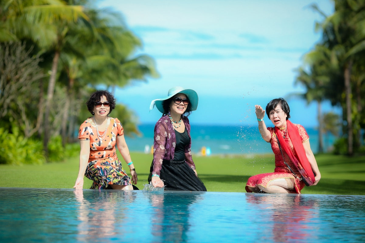 three women sitting on the edge of a swimming pool