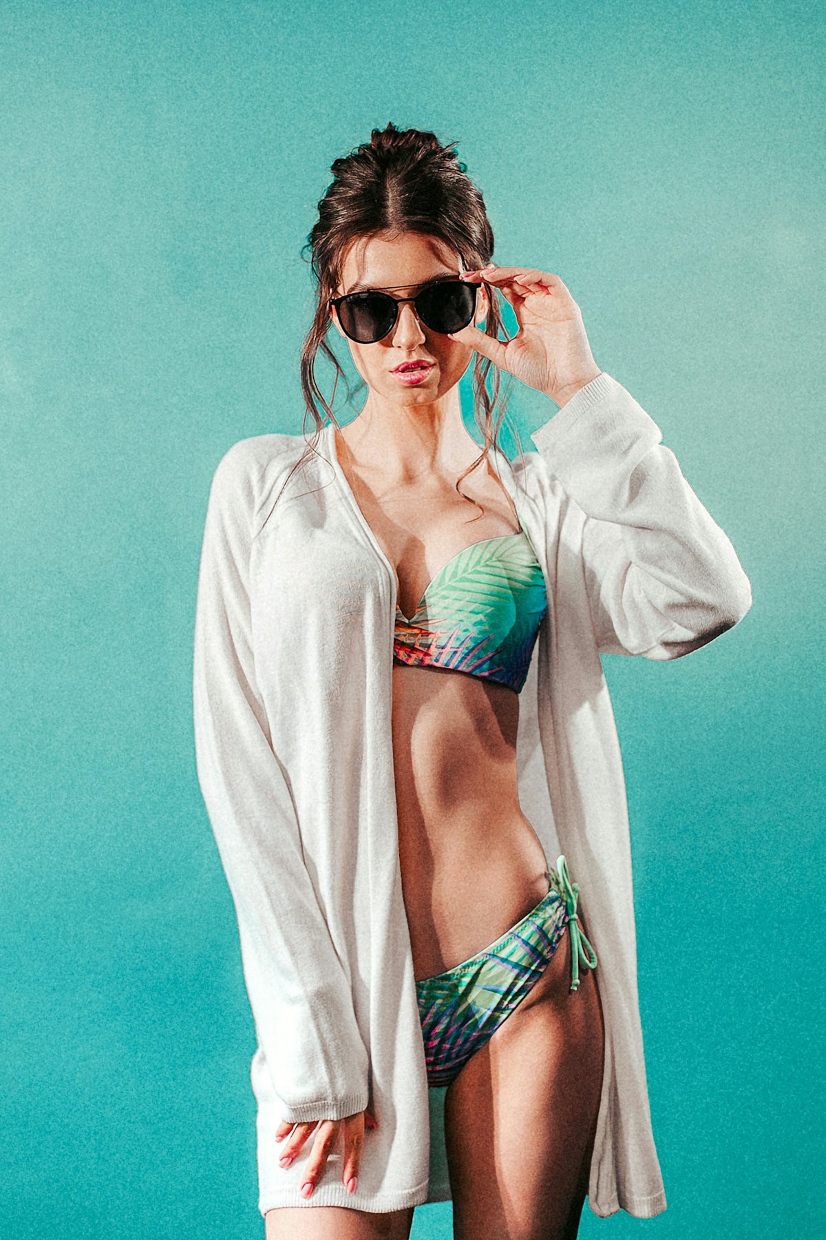 a woman in a bikini and cardigan posing for a picture