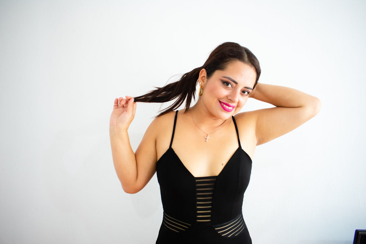 a woman in a black bodysuit holding her hair