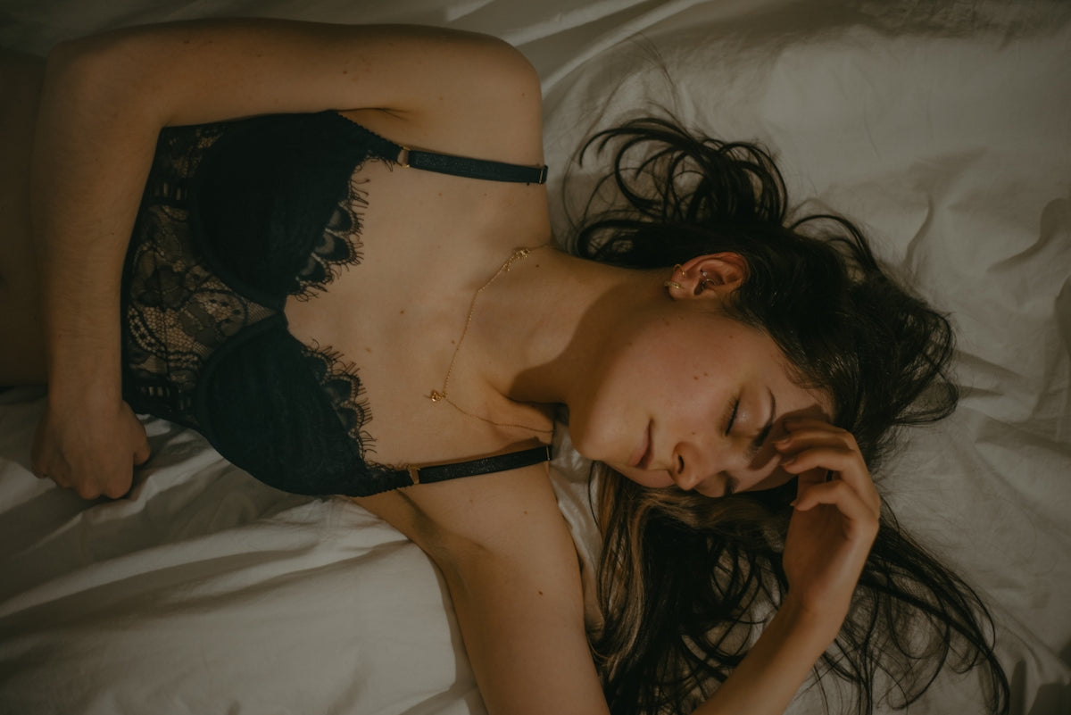 a woman laying on a bed wearing a black lingerie