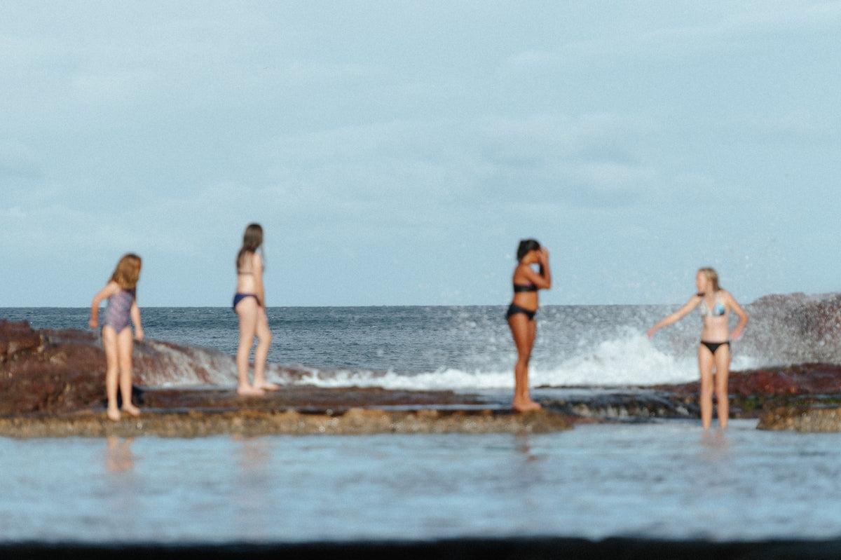 a group of women standing on top of a beach next to the ocean