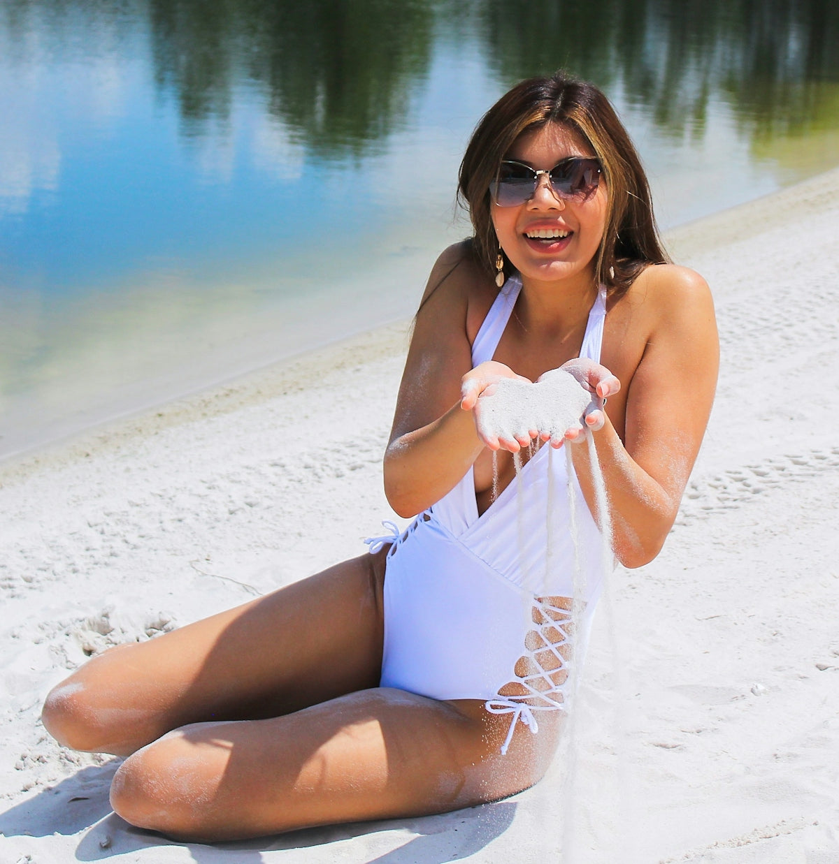 a woman in a white swimsuit sitting on the beach