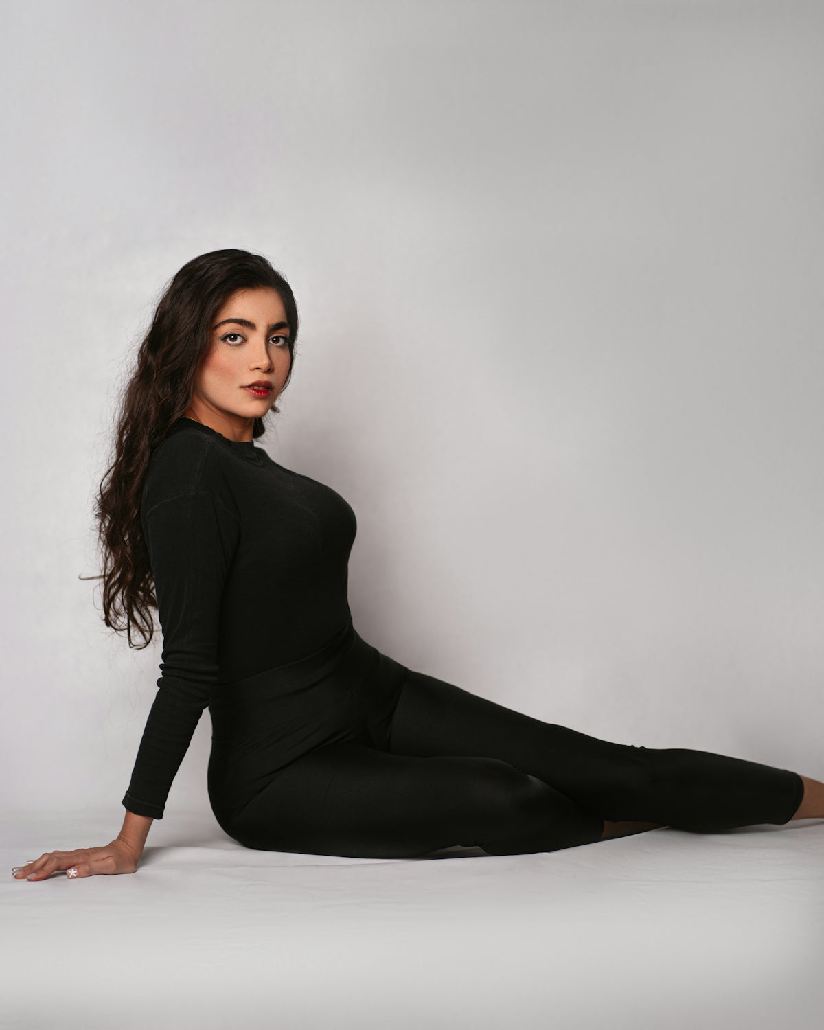 a woman in a black bodysuit is sitting on the floor
