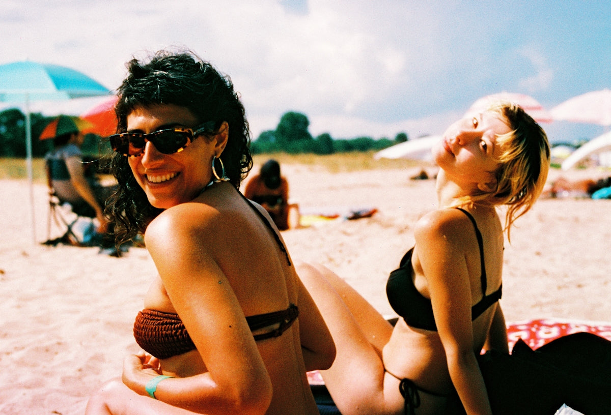 A couple of women sitting on top of a sandy beach