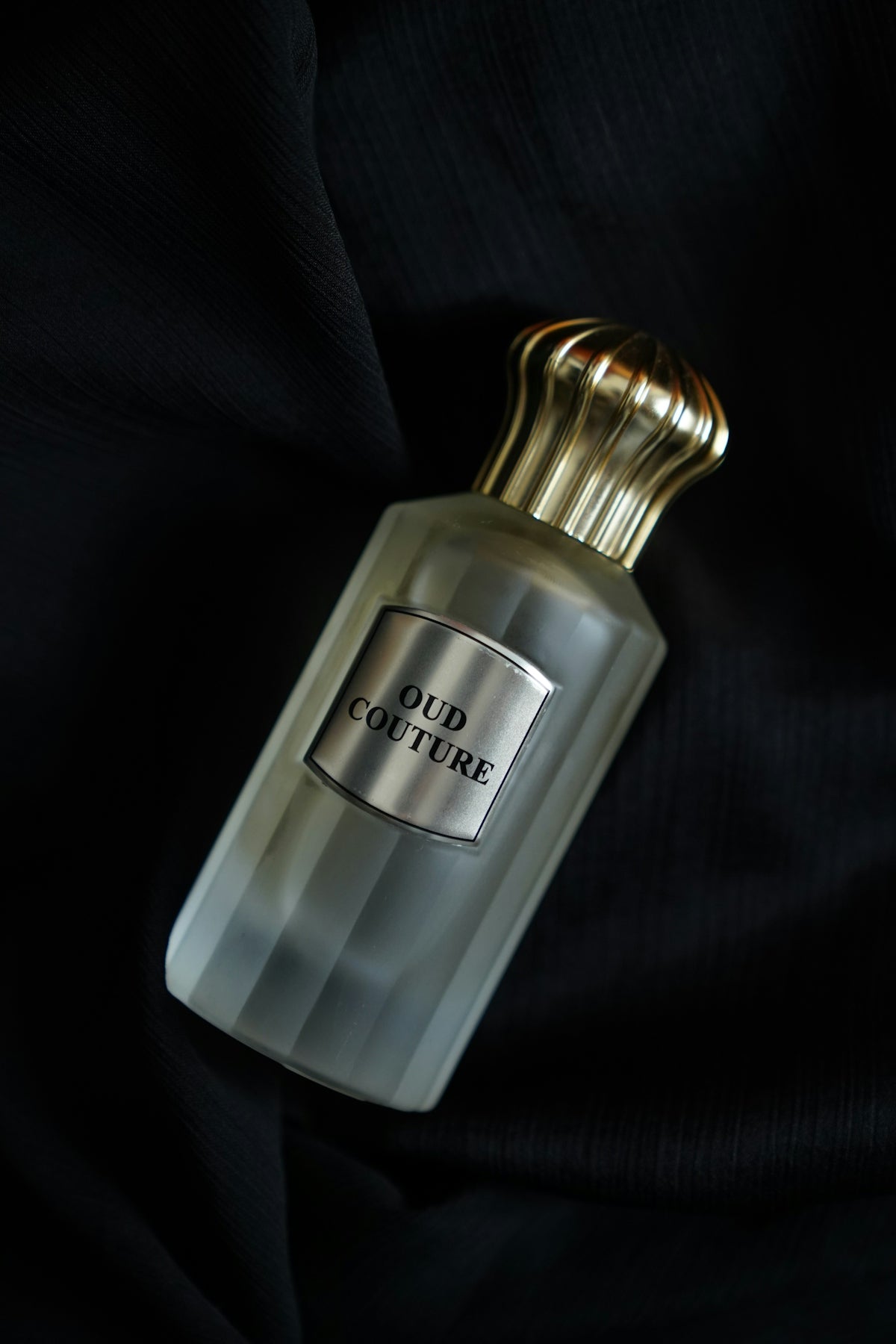 A bottle of cologne sitting on a black cloth