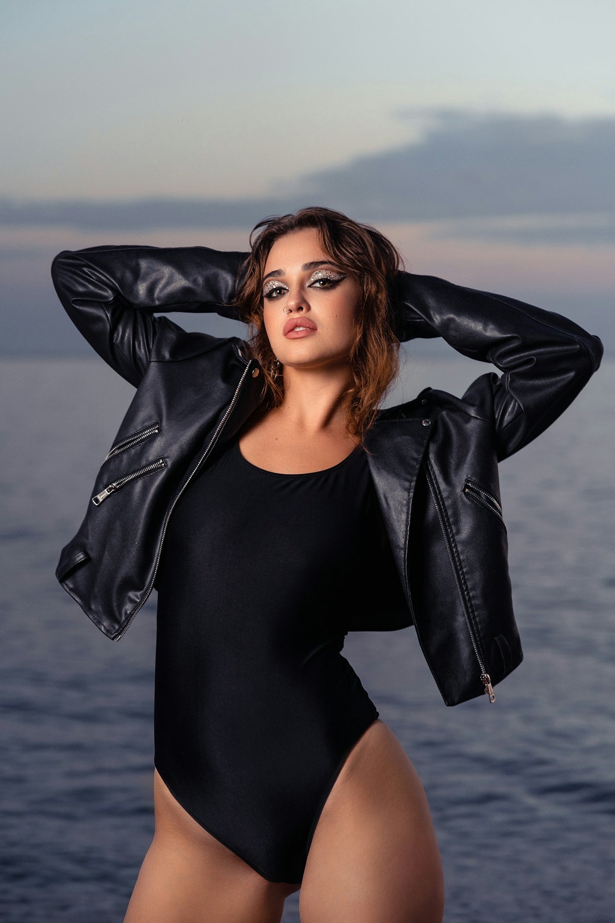 Woman in black bodysuit and leather jacket by the sea