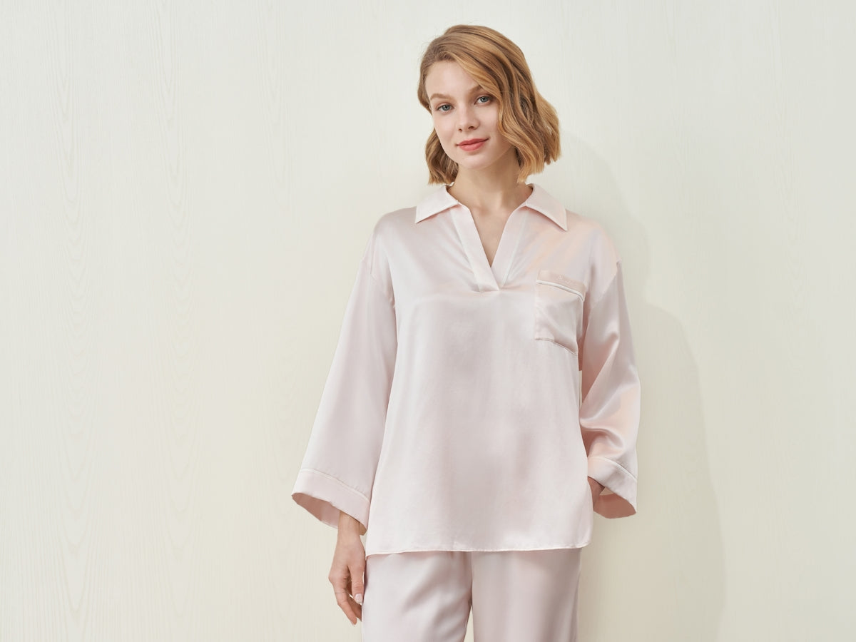 A woman in a light pink silk pajama set.