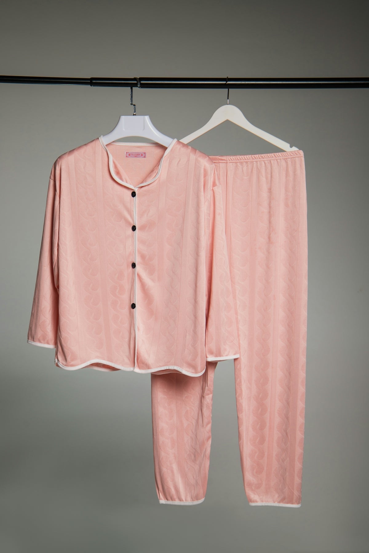 Pink pajama set with white trim hanging