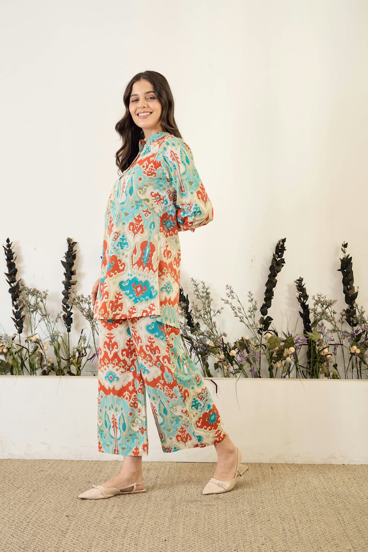 A woman in a patterned pajama set smiles.
