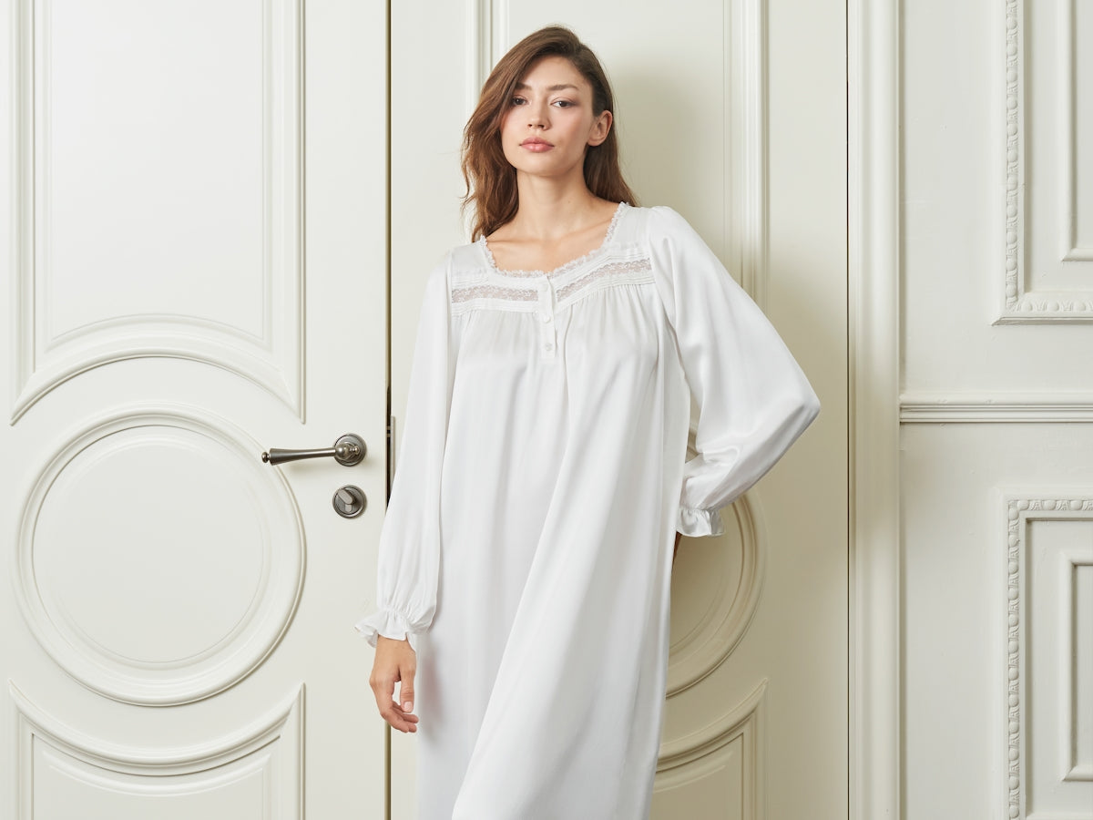 A woman in a white nightgown stands by a door.