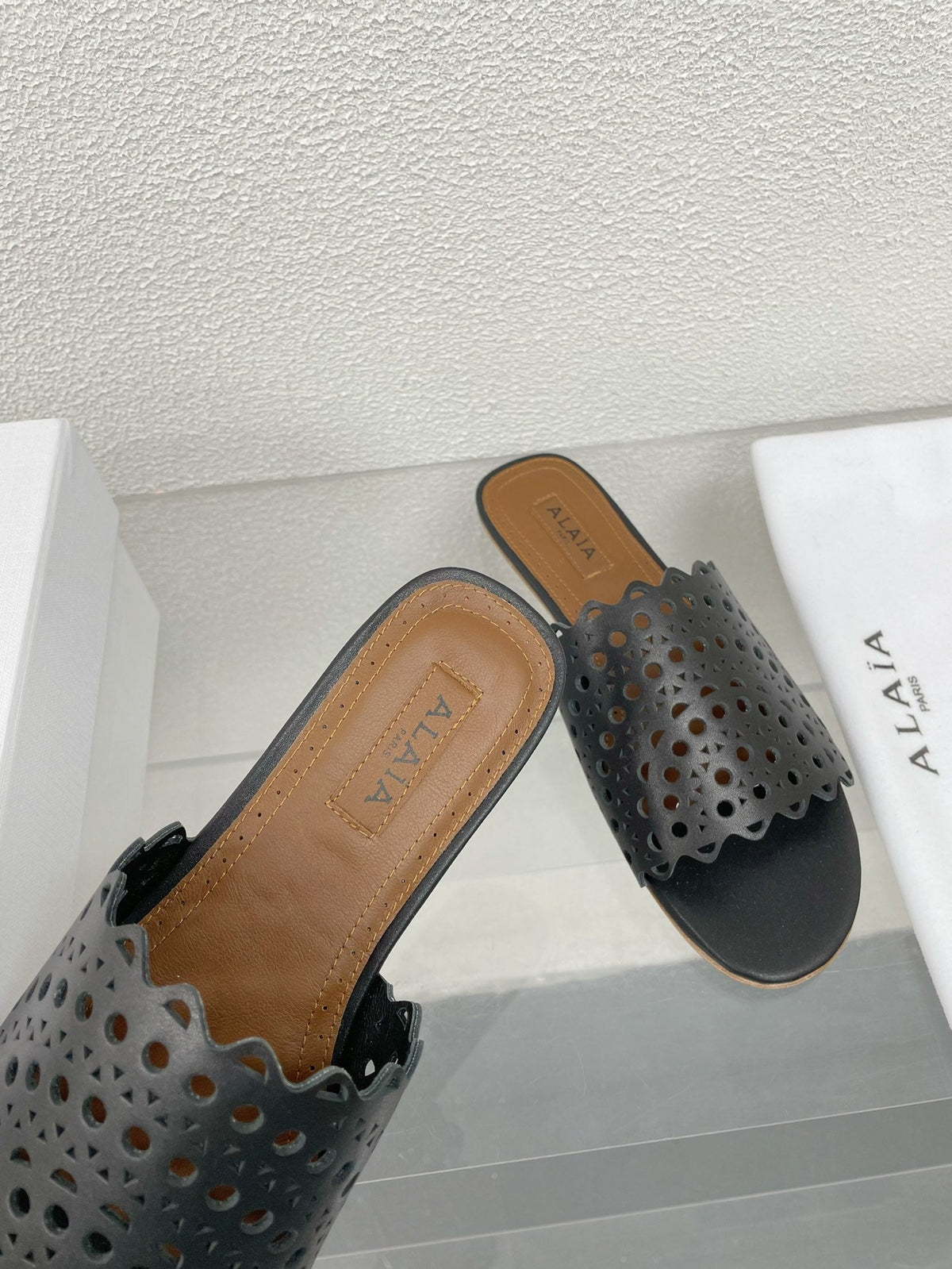 ALAIA VIENNE FLAT MULES IN BLACK LAMBSKIN